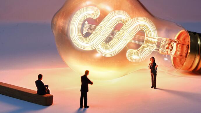 Three business people stand in front of a light bulb with a paragraph symbol.