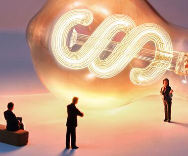Three business people stand in front of a light bulb with a paragraph symbol.