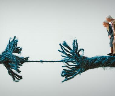 The graphic shows a pair of figures standing on a string that is about to break.