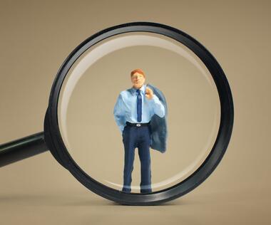 The picture shows a magnifying glass enlarging an interim manager.