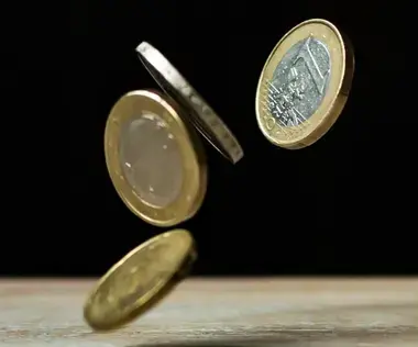 Solving financial challenges with interim management: The picture shows coins falling onto a table.