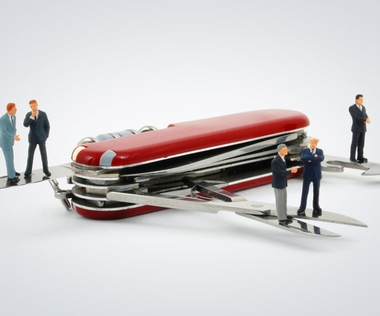 HR Shared Service Center: Das Bild zeigt mehrere Figuren, die um ein Schweizer Taschenmesser herumstehen.