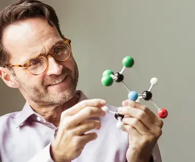 Mastering business challenges with interim management: The picture shows a man with a molecule model in his hands.