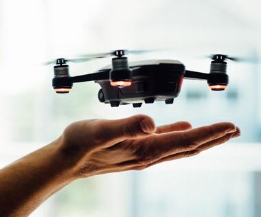 Interim Management Operations: The picture shows a small drone hovering just above an outstretched hand, ready to take off or land.