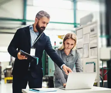 Interim Management Operations: The picture shows an Operations Manager showing his colleague something on a laptop.