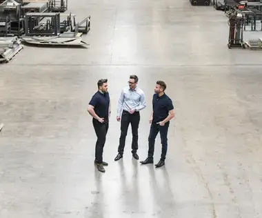 Interim Management Opertaions: The picture shows a bird's eye view of three men in a production hall.