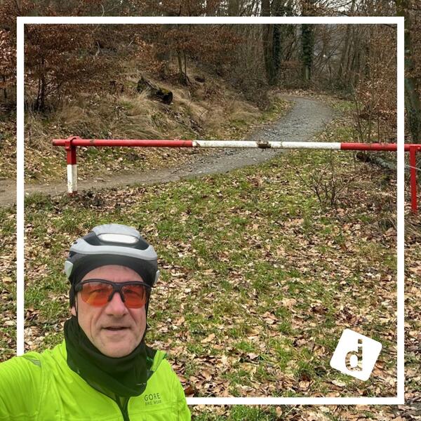 Das Bild zeigt den Radfahrer Tilo Ferrari vor einer Schranke im Wald.