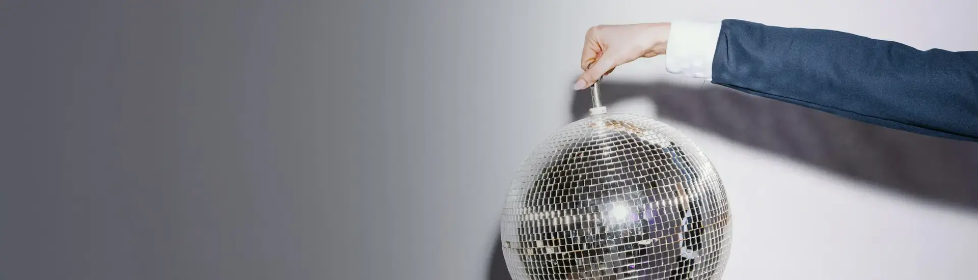 Interim Management Marketing: The picture shows a woman's arm. The woman is lifting a silver disco ball into the air.