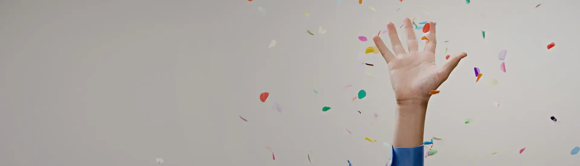 Interim Management Compensation and Benefits: The picture shows a hand stretched upwards with confetti in the background.
