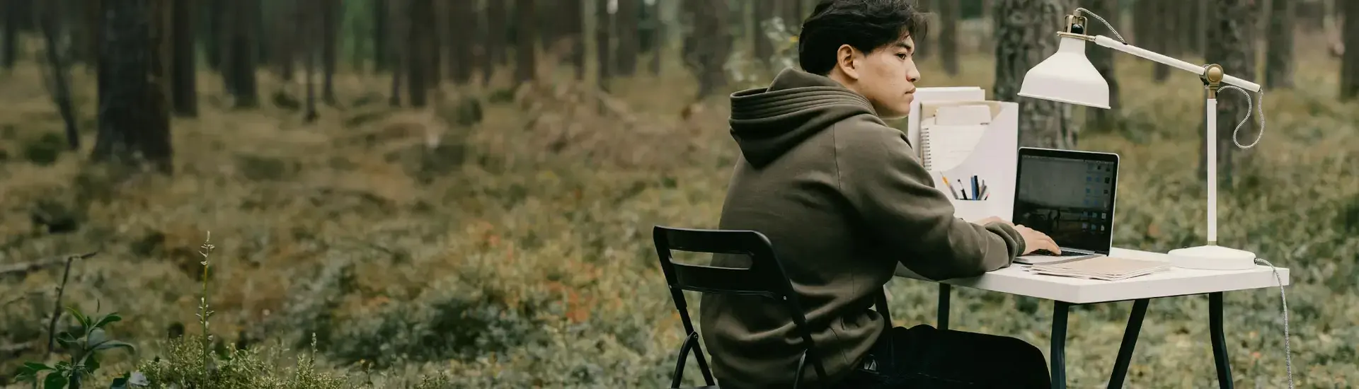 Interim ESG Management: Das Bild zeigt einen ESG Manager an einem Schreibtisch im Wald sitzend.