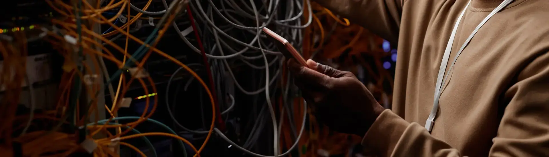 Interim IT Security Management: The picture shows a young man in a server room with tons of cables.