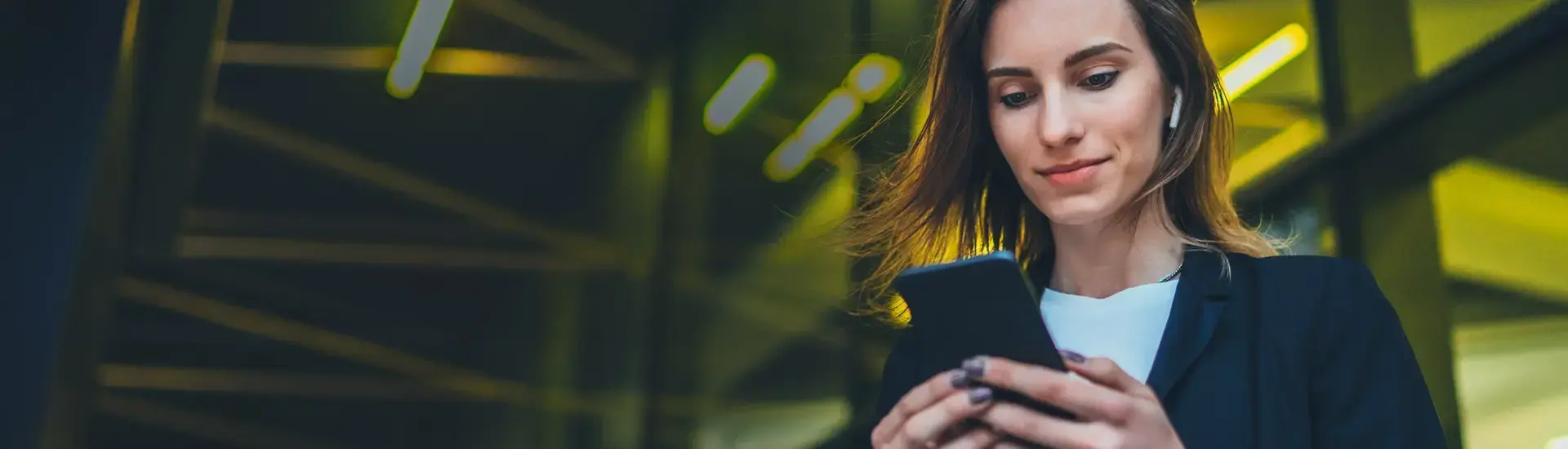 The picture shows a young woman looking at her smartphone.