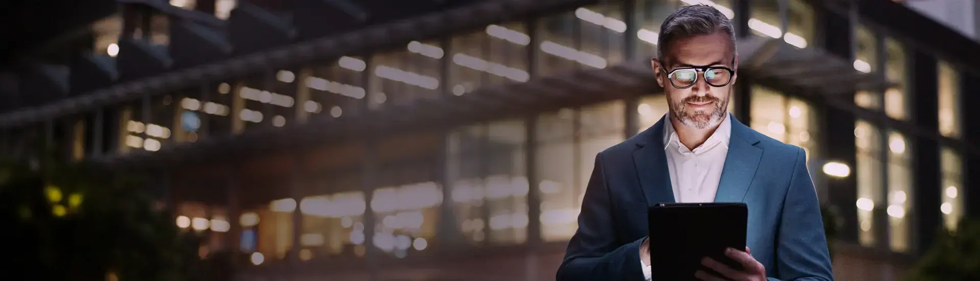 Interim CDO: The picture shows an interim CDO standing in front of an office building in the evening and reading something on his tablet.