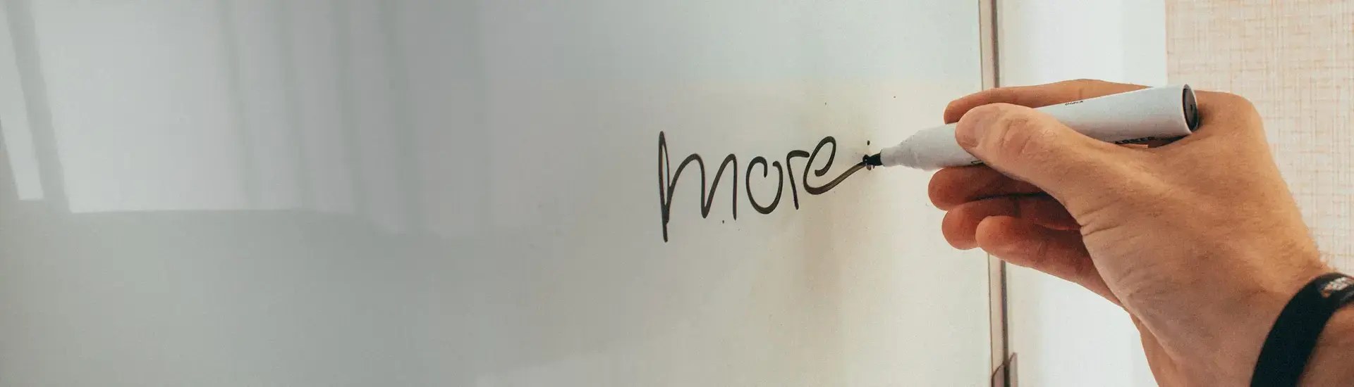 Interim Business Development: The picture shows a person writing the word "more" on a whiteboard.