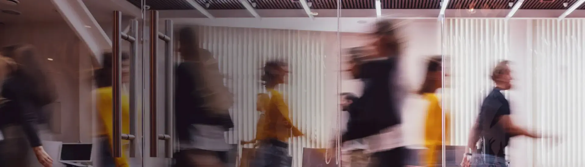 The blurred image shows people walking along an office corridor.