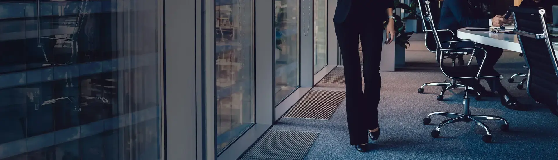 DAs Bild zeigt eine Geschäftsfrau von der Hüfte abwärts in einem Büro.