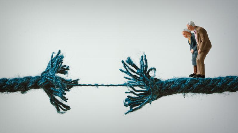 The graphic shows a pair of figures standing on a string that is about to break.