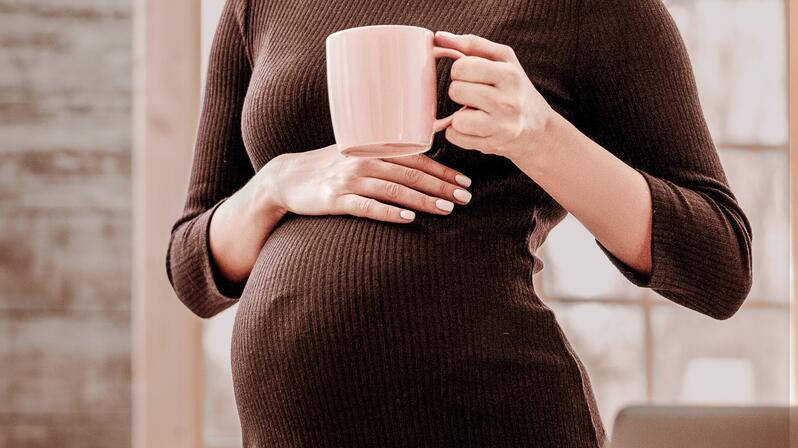 Parental leave replacement: The picture shows a pregnant woman placing a coffee cup on her stomach.