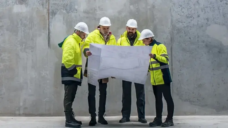 Solving business challenges with interim management: The picture shows workers studying a construction plan.