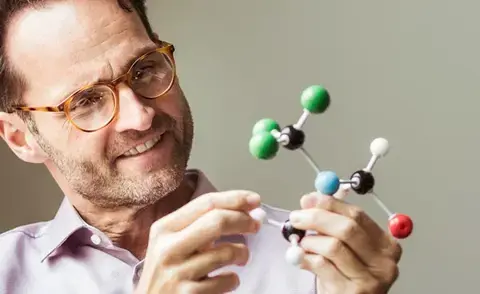 Mastering business challenges with interim management: The picture shows a man with a molecule model in his hands.
