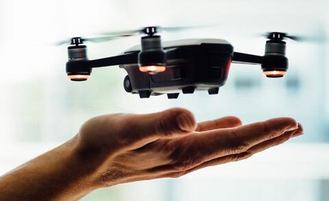 Interim Management Operations: The picture shows a small drone hovering just above an outstretched hand, ready to take off or land.