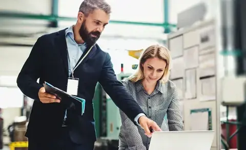 Interim Management Operations: The picture shows an Operations Manager showing his colleague something on a laptop.