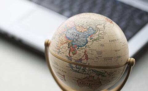 Interim Management: The picture shows a desk with a laptop and a small globe.