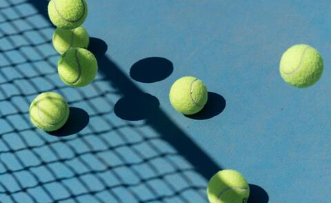 Interim Management: The picture shows a tennis court with several tennis balls.